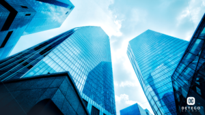 A view from the ground looking upward at blue toned skyscrapers reaching toward clouds