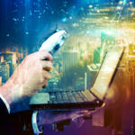 A white businessman's hand holds a magnifying glass over a lpatop as digital data surrounds a cityscape